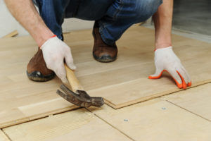 Laying hardwood parquet. Installer clamps parquet with a hammer.
